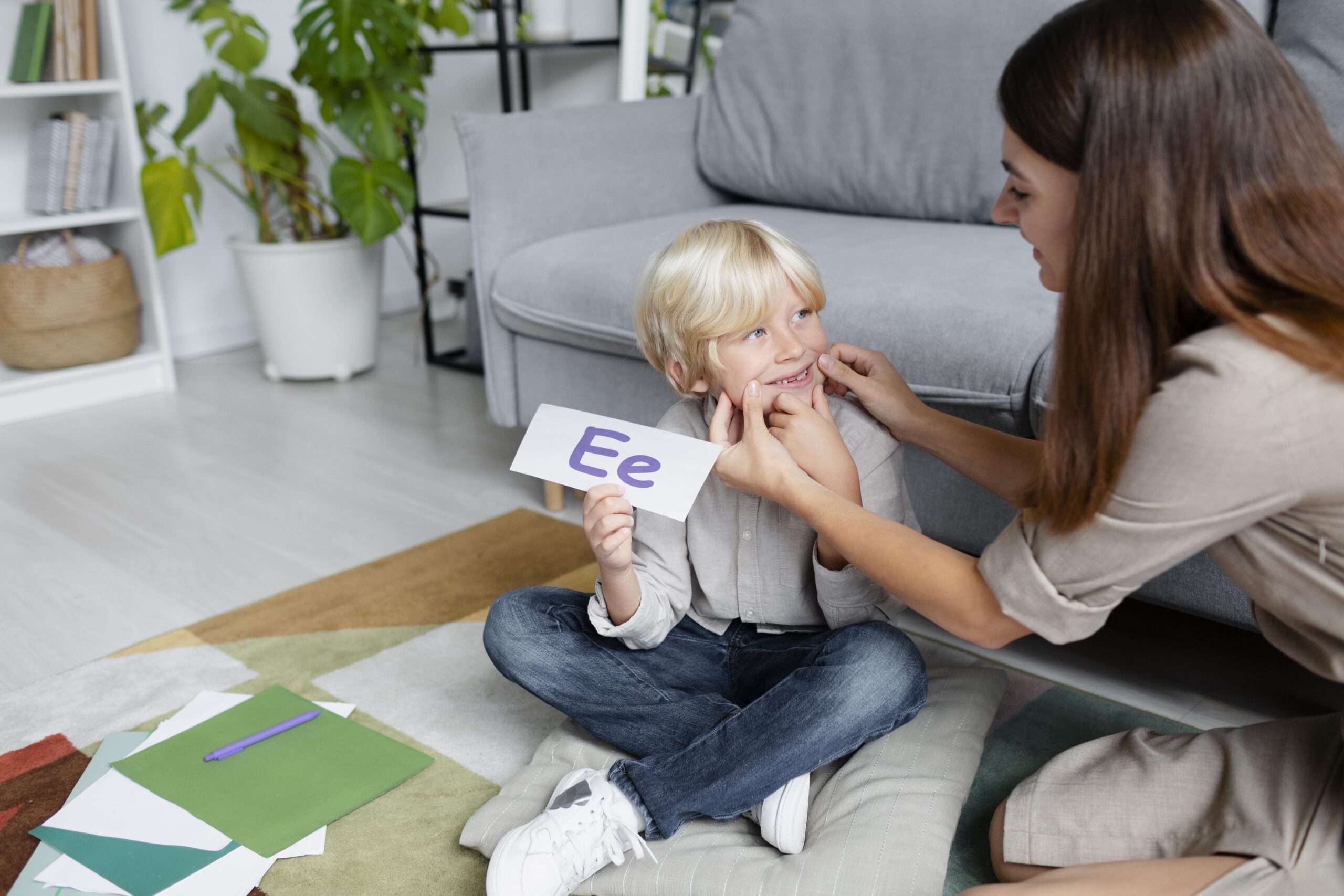 young-woman-doing-speech-therapy-with-little-blonde-boy-min